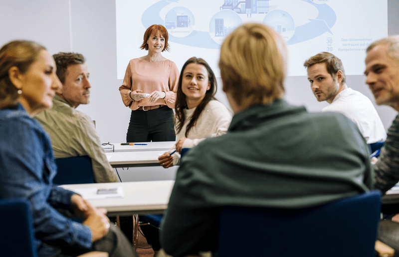 Teilnehmende eines VdS-Lehrgangs im Seminarraum mit Dozentin, steht für praxisnahe Weiterbildung mit direktem Austausch, fundierter Wissensvermittlung und persönlichem Lernerfolg im Bereich Brandschutz, Security, Cyber-Security, Elektrische Anlagen, Arbeitsschutz und Naturgefahren.