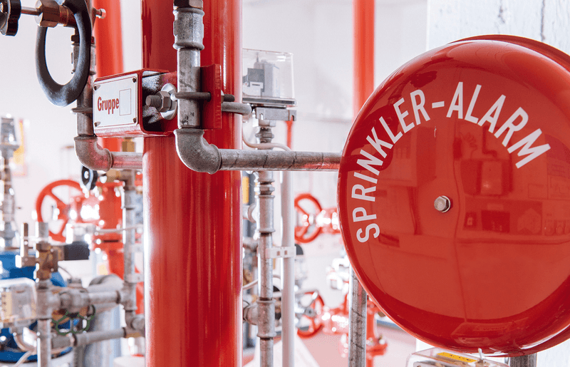 Teilnehmende eines VdS-Lehrgangs zum anlagentechnischen Brandschutz bei einer praktischen Übung an einer Brandschutzanlage.